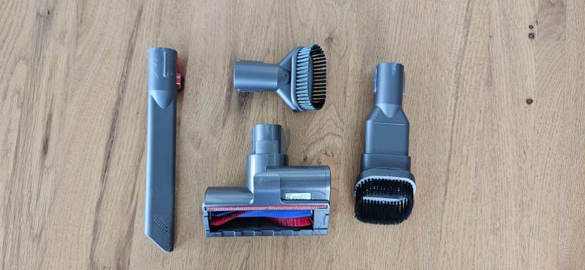 Ein Bürstenset eines getesteten Dyson Staubsaugers liegt im Viereck angeordnet auf einem Holzboden.