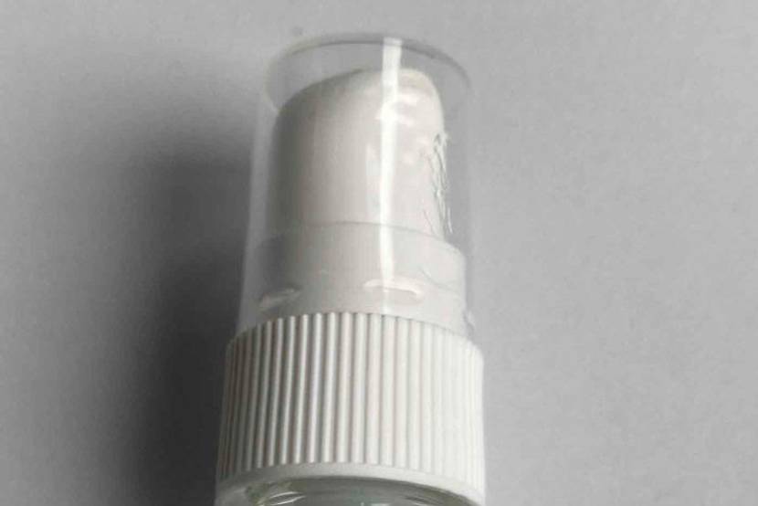 Hyaluron-Serum mit Pumpspender liegend auf einer grauen Oberfläche.