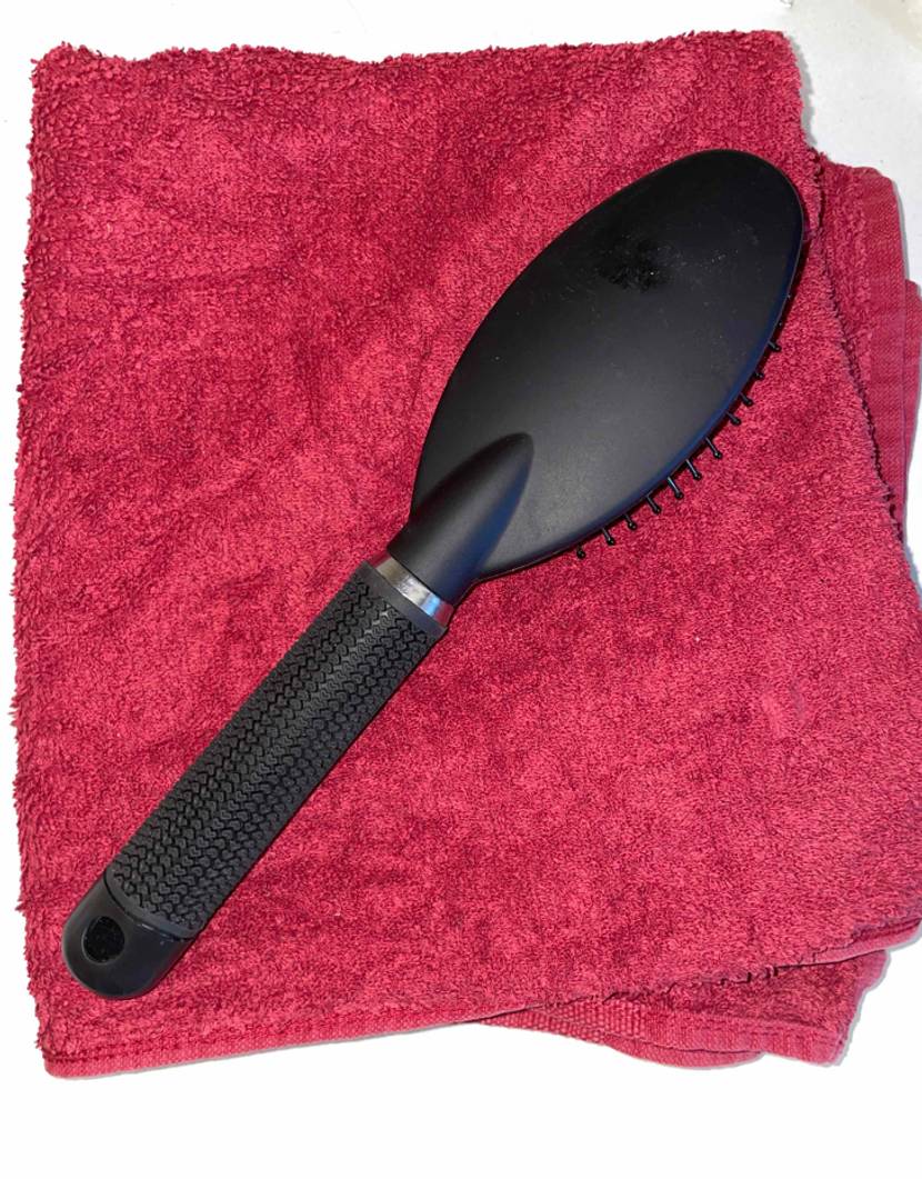 Haarbürste mit Borsten nach unten zeigend auf einem Handtuch