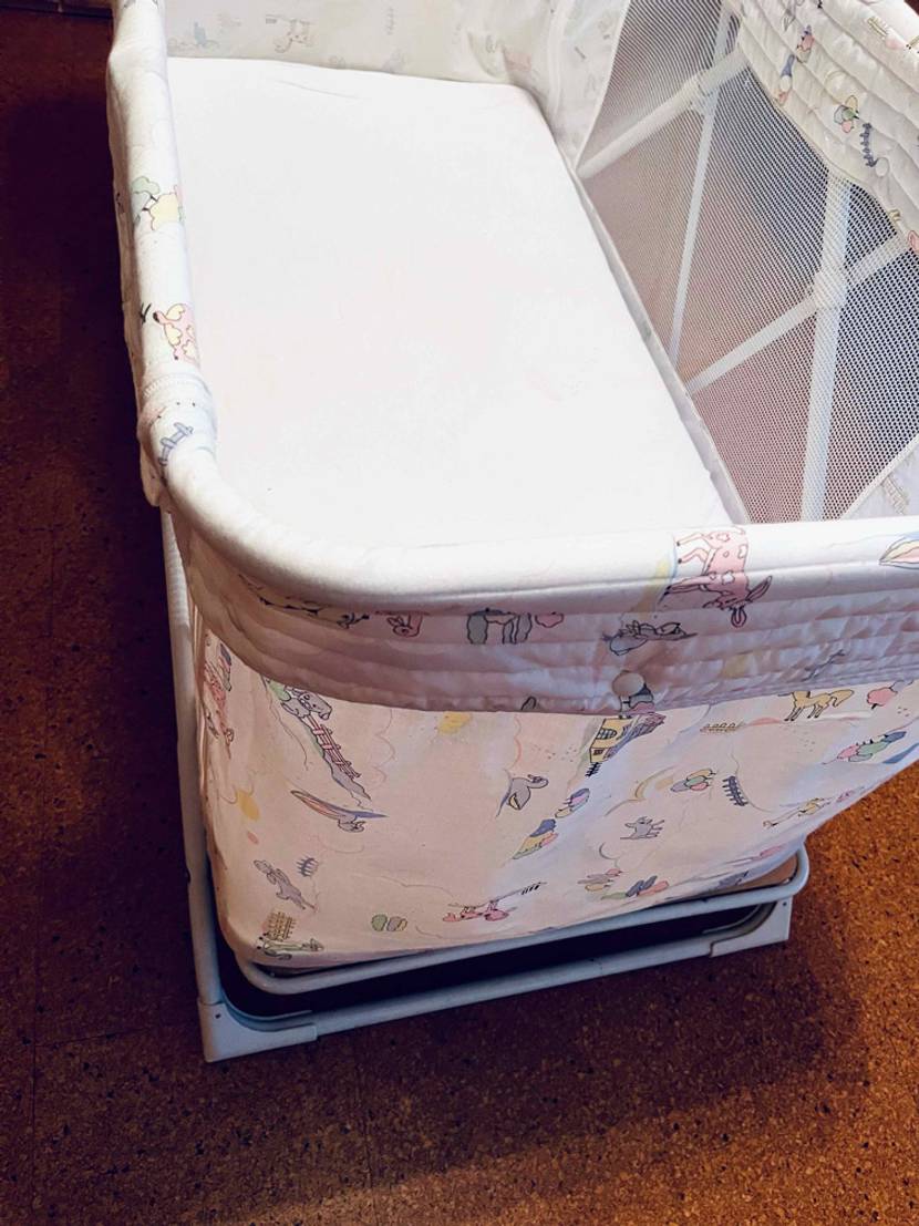 Auf einem Holzboden steht ein getestetes Baby-Reisebett.