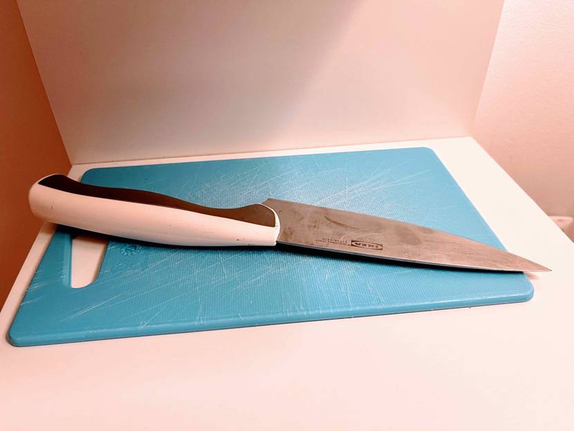 Küchenmesser getestet: Ein Messer liegt auf einem blauen Schneidebrett auf heller Oberfläche