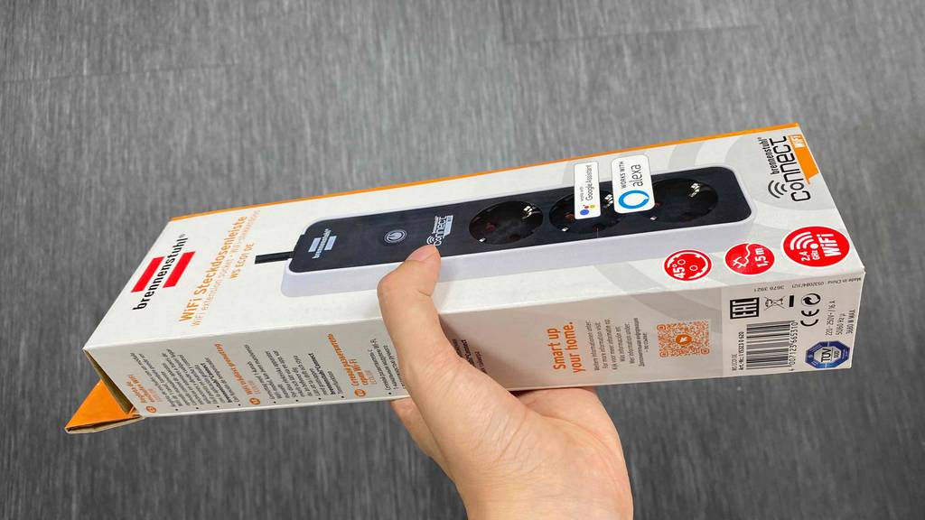 WLAN-Steckdose in der Hand über grauem Boden gehalten