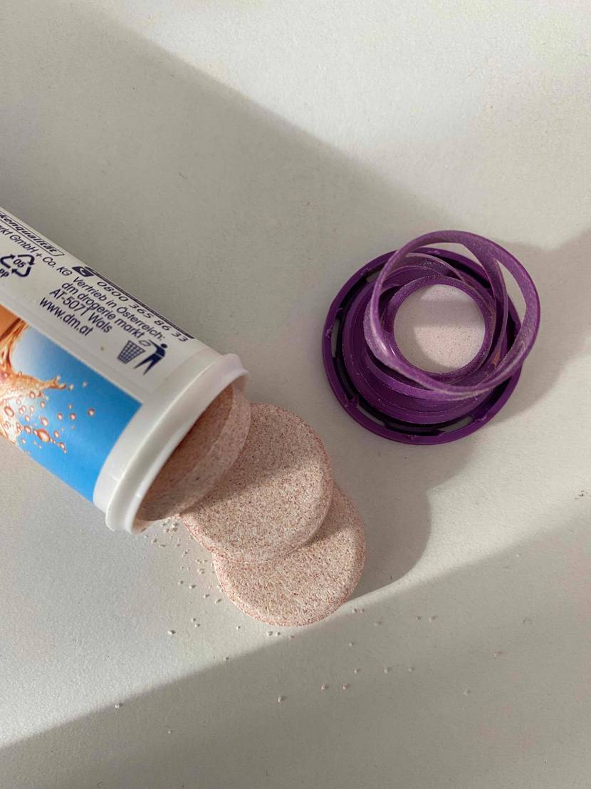 Multivitamin-Tabletten im Test: Eine Packung Multivitamin-Tabletten liegt geöffnet auf einer hellen Oberläche einige Tabletten liegen daneben