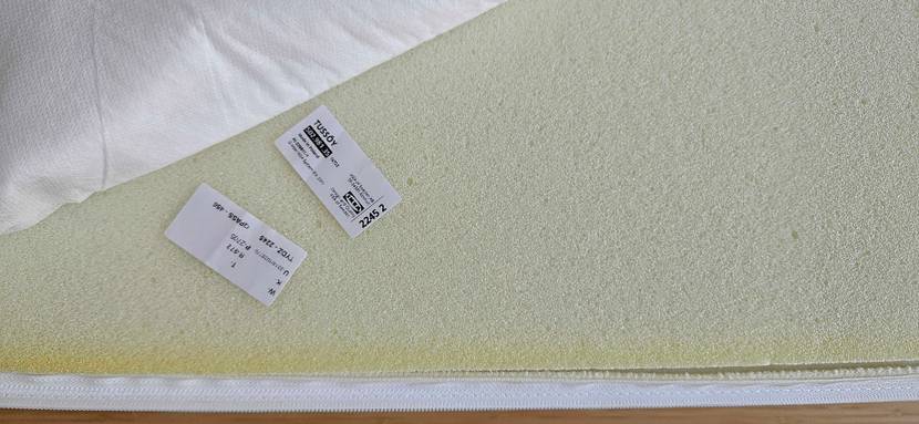 Topper-180x200 im Test: zwei Schilder mit Produktnamen und darauf liegen auf geöffnetem Topper.