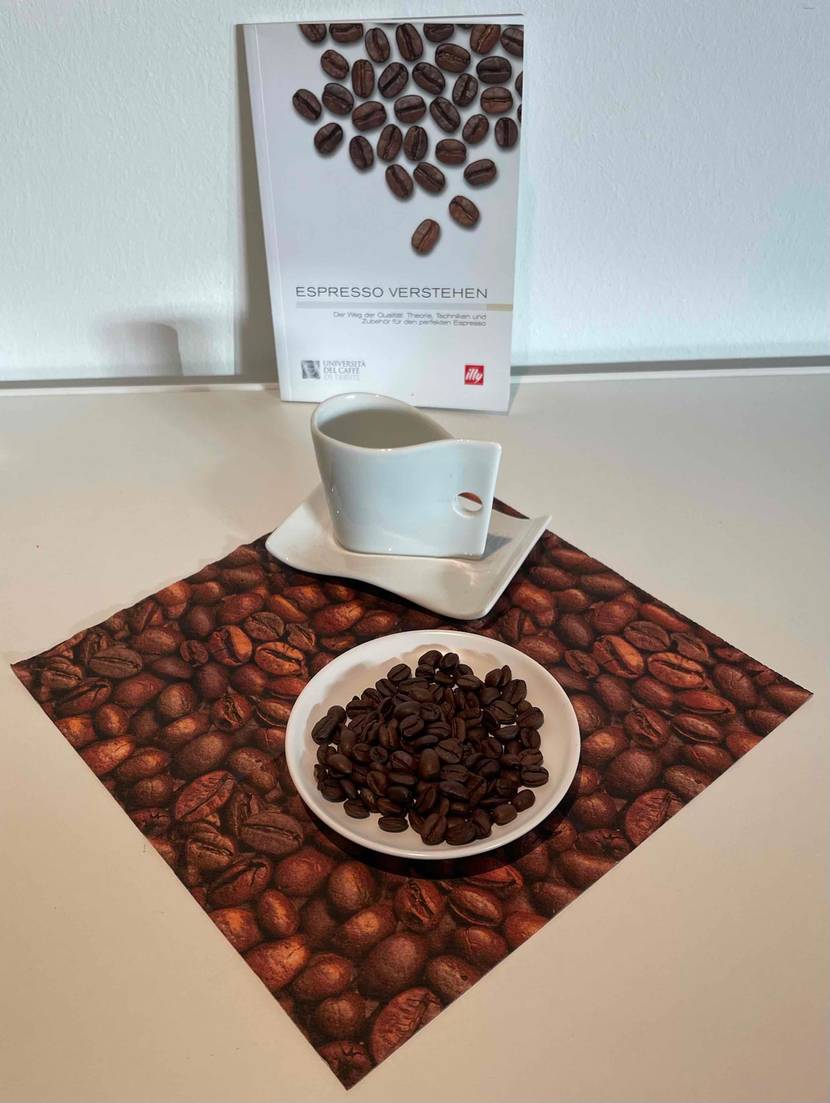 Espressobohnen getestet: Ein Buch lehnt an der Wand im Vordergrund eine Tasse und ein Teller