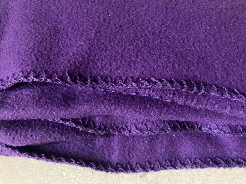 Decke-mit-Ärmel-Test: violette Decke zusammengefaltet mit Fokus auf Material.