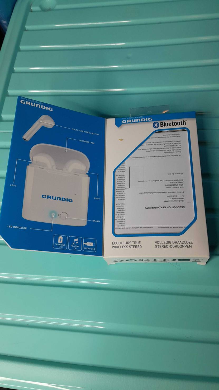 In-ear-noise-cancelling-Kopfhörer im Test: geöffnete Verpackung von In-ear-noise-cancelling-Kopfhörern auf einem blauen Untergrund liegend.