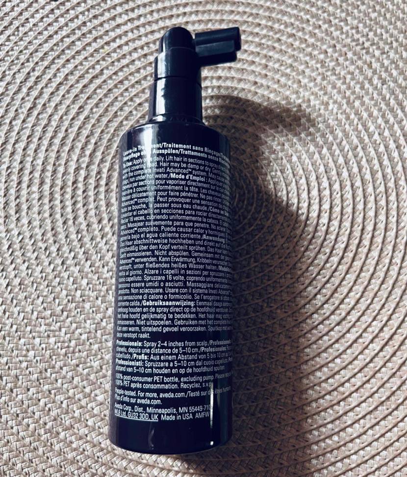 Haarwuchsmittel im Test: Haarwuchsmittel in einem Pumpspender von der Rückseite liegend auf einem Tischset.