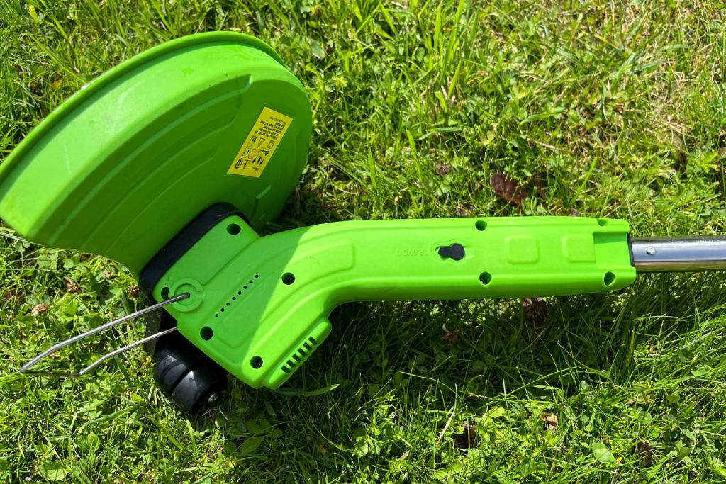 Akku-Rasentrimmer Detail von unterer Abdeckung im Gras liegend