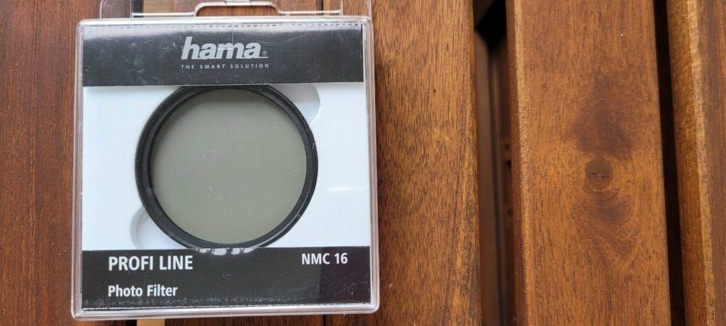 Getesteter Polfilter von Hama liegt ain der Verpackung auf einem Holzuntergund.