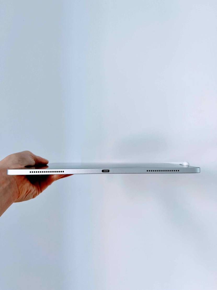 Tablet mit Stift im Test: Eine Hand hält eine Tablet mit der Unterseite nach vorne gegen eine helle Wand