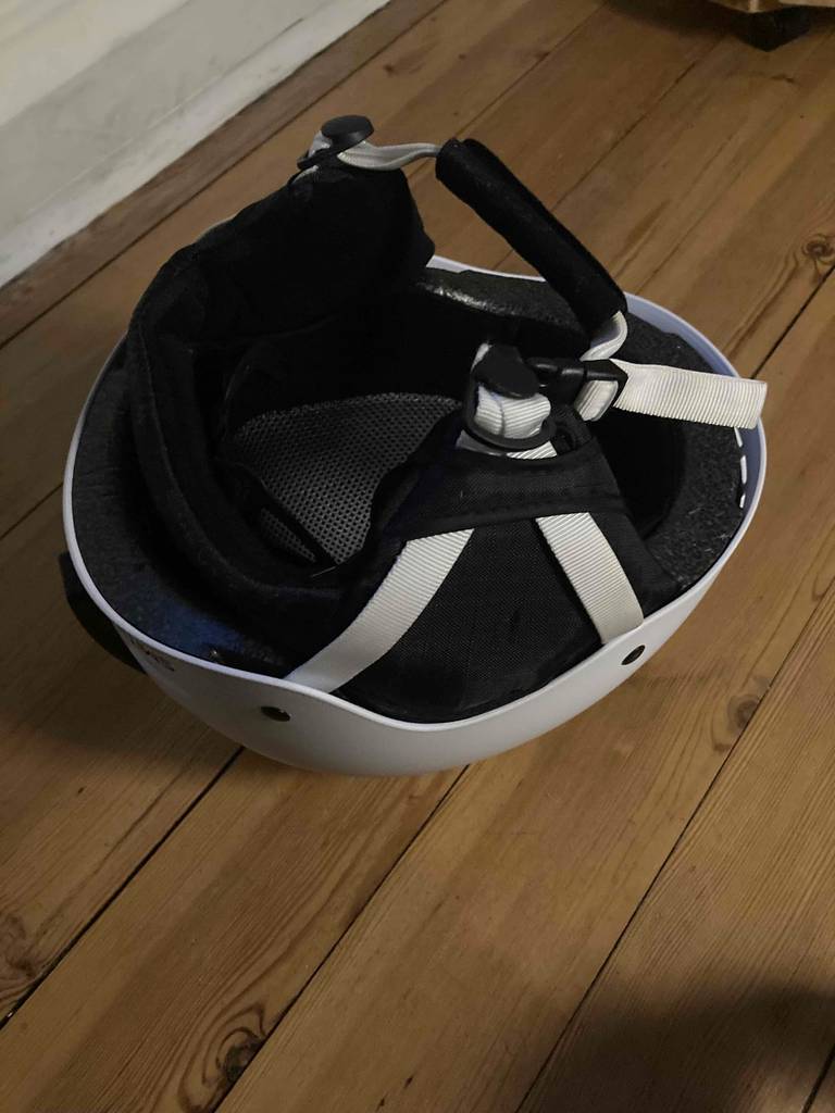 Snowboardhelm getestet: Ein weißer Snowboardhelm liegt verkehrt herum auf einem Boden.