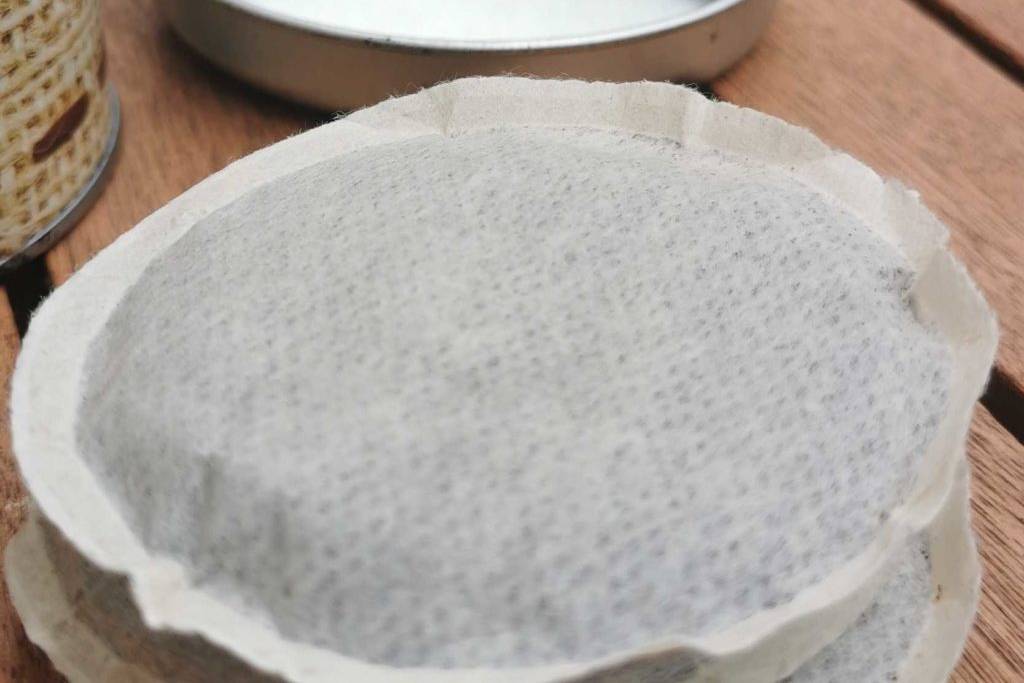 Zwei Kaffeepads auf einem Tisch übereinander und im Hintergrund Dose von Aufbewahrungsdose.