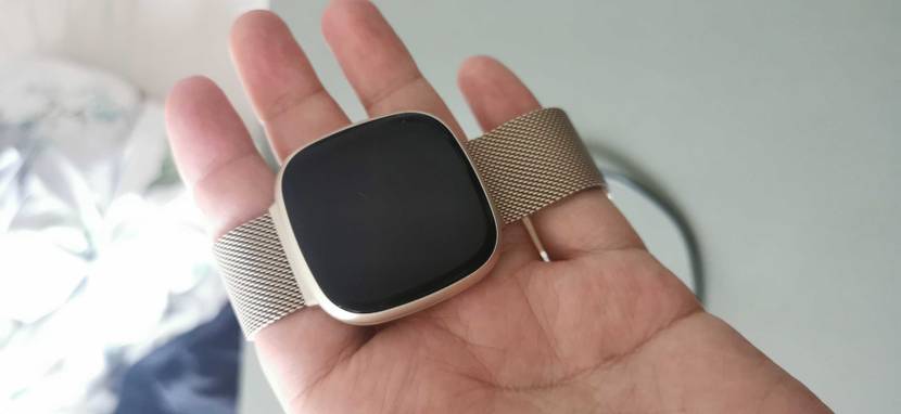 Hand hält eine getestete Fitbit-Uhr mit ausgeschaltetem Display.