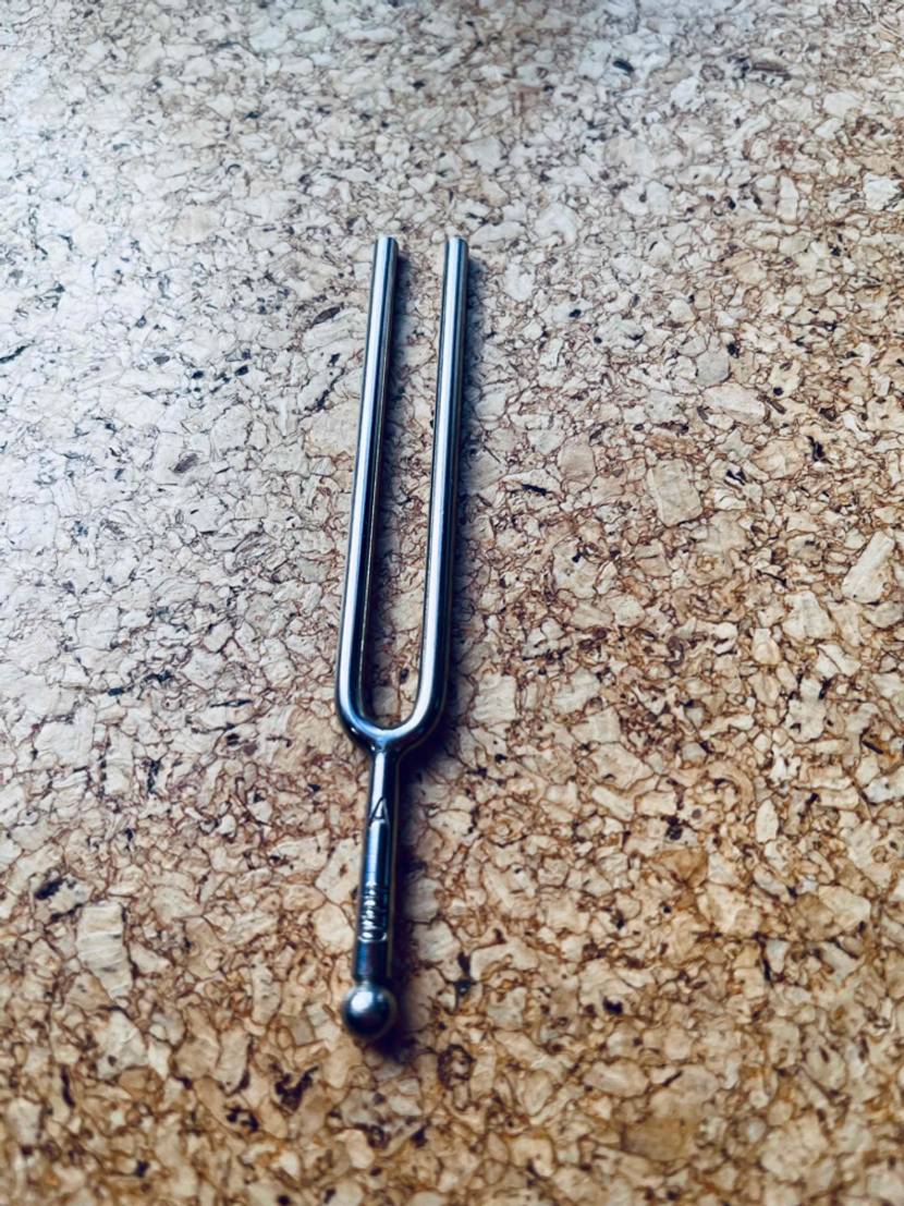 Auf einer Holzoberfläche liegt eine getestete Stimmgabel.
