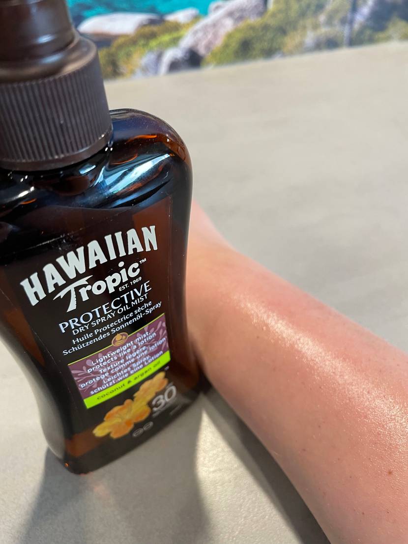 Sonnenspray und eingecremter Arm.