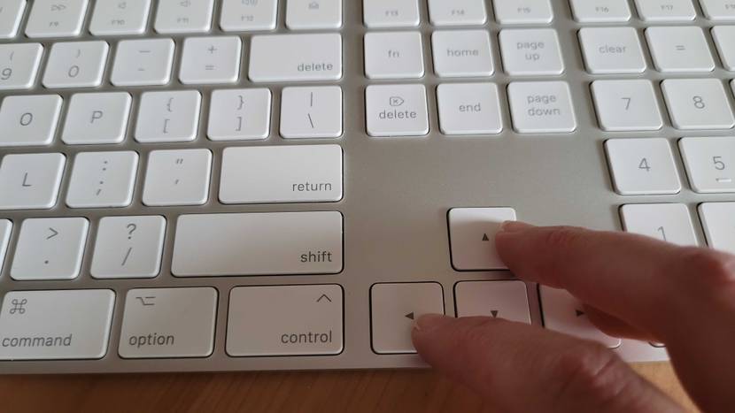 Zwei Finger zeigen auf die Richtungstasten einer getesteten Tastatur.