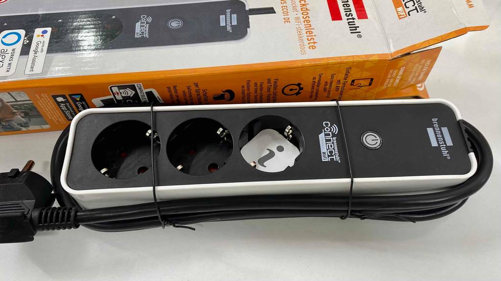 WLAN-Steckdose liegt auf weißer Fläche neben der Verpackung