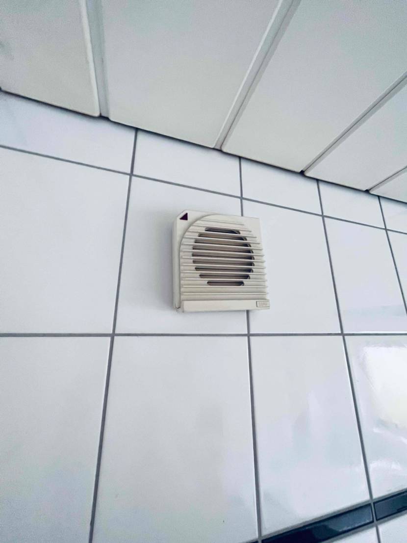 An einer Fließenwand befindet sich ein getesteter Badlüfter.