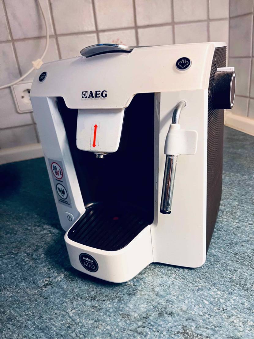 Gesamtansicht einer getesteten AEG-Kaffeemaschine in Weiß. Sie befindet sich auf einer blauen Arbeitsfläche vor weißen Fliesen.