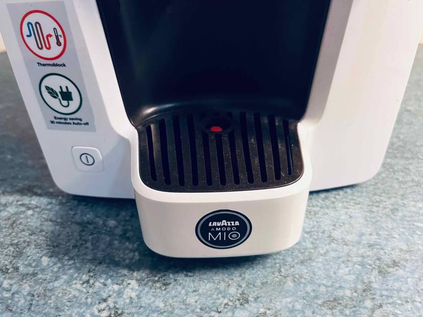 Kaffeemaschine-Test: Detailansicht der unteren Sammelschale und der Einschalttaste einer weißen Kaffeemaschine mit Thermoblock.