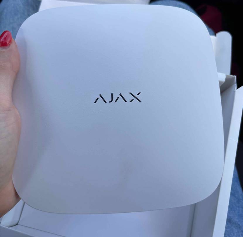 Eine Hand hält die getestete Ajax-Alarmanlage hoch.