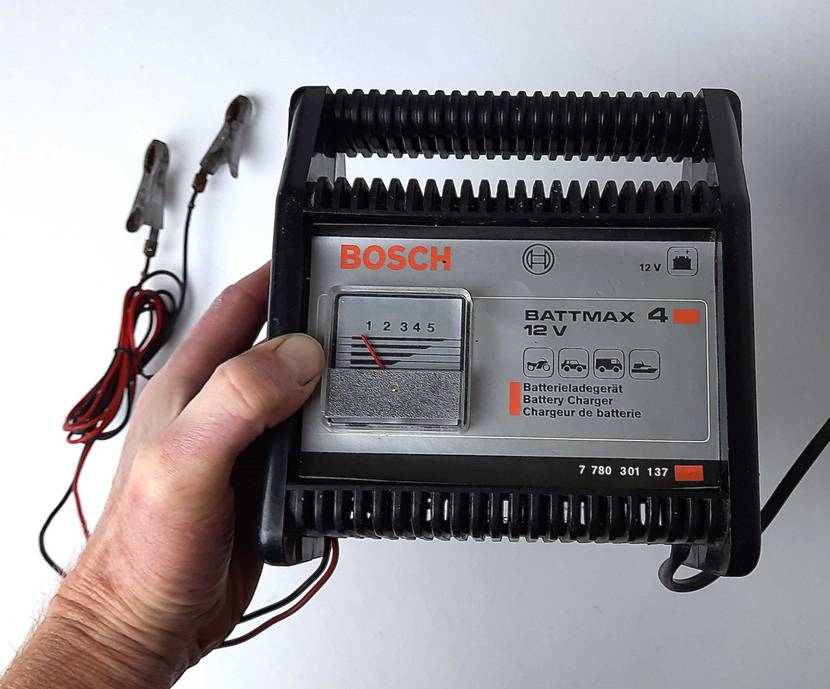 Das getestete Autobatterie-Ladegerät von einer Hand gehalten.