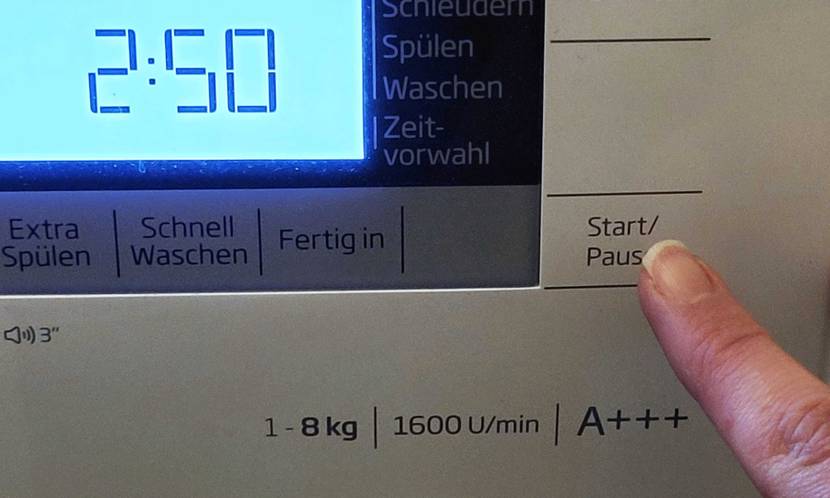 Beko Waschmaschine getestet: Nahaufnahme eines Fingers der den Start-Knopf drückt.