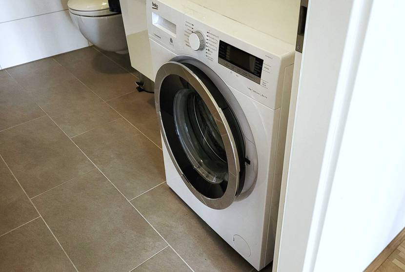 Eine getestete Beko Waschmaschine neben einem Türrahmen in einem Badezimmer.