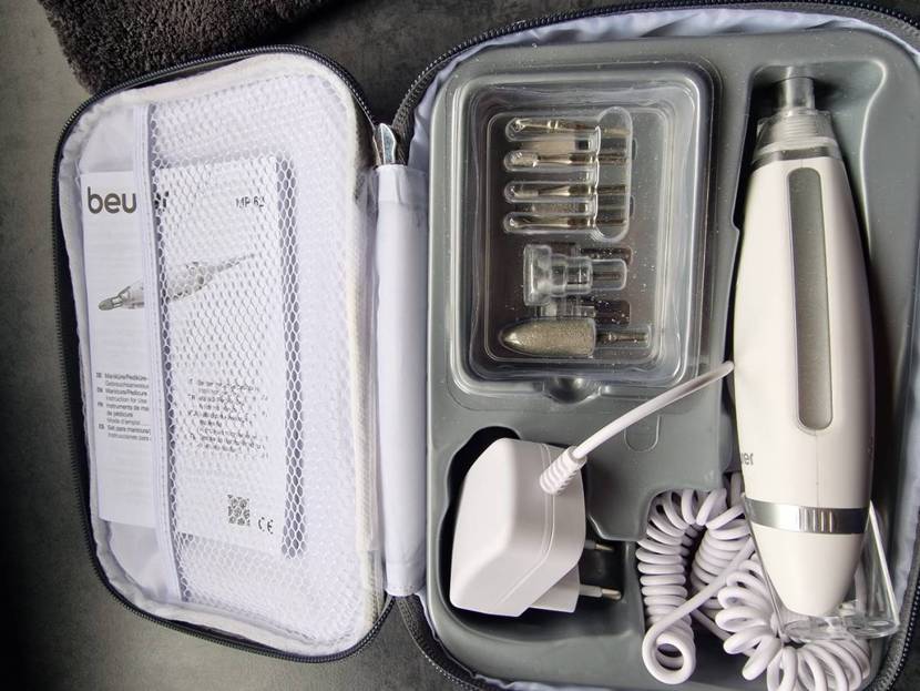 Maniküre-Set im Test: Nahaufnahme der geöffneten Beurer MP 62 Aufbewahrungstasche inklusive elektrischem Maniküre-Gerät, mehreren Aufsätzen, Betriebsanleitung und Adapter.