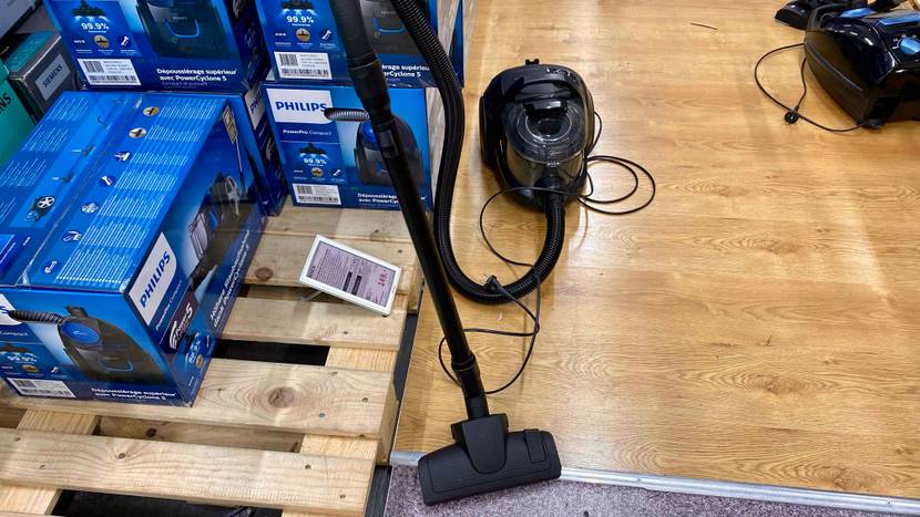 Ein getesteter Bosch-Staubsauger steht auf einer Holzoberfläche neben mehreren verpackten Geräten in einer Verkaufssfläche.