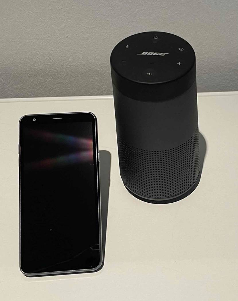Getestet: Ein Bose Bluetooth Lautsprecher steht neben einem Handy auf weißer Fläche.