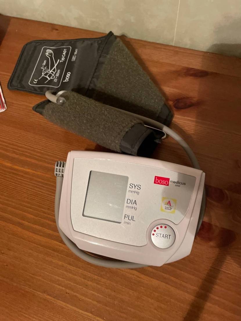 Boso Medicus Uno Blutdruckmessgerät getestet: Ansicht von oben eines hellen Modells inklusive Manschette auf einem Holzuntergrund.