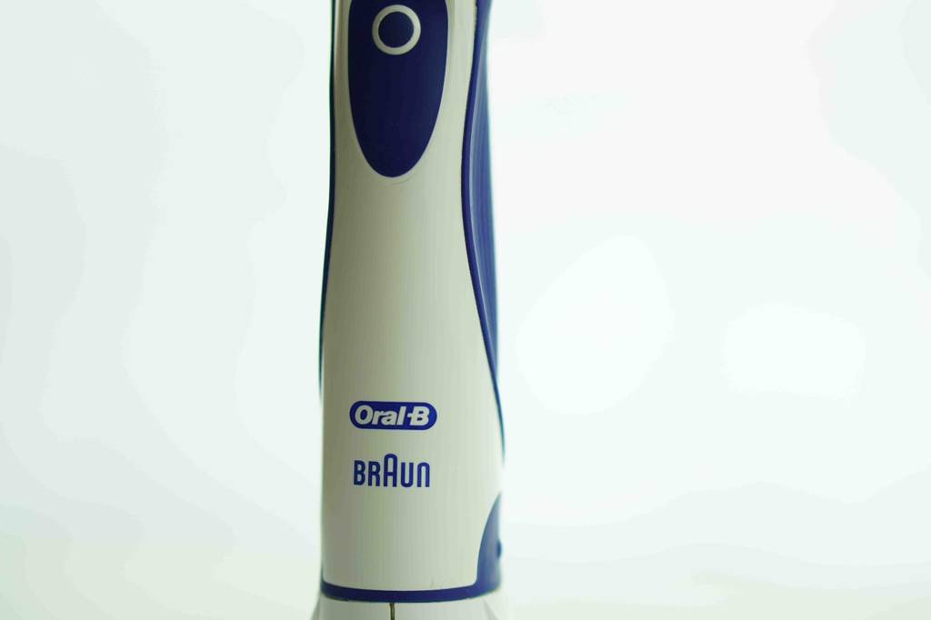 Nahaufnahme des Griffs inklusive Einschaltknopf einer elektrischen Oral-B Zahnbürste von Braun.