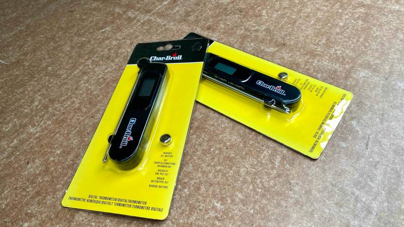 Zwei gelbe Verpackungen mit digitalen Char-Broil Grillthermometern im Test, inklusive eingeschweißter Knopfbatterie, liegen auf einer beigefarbenen Fläche.