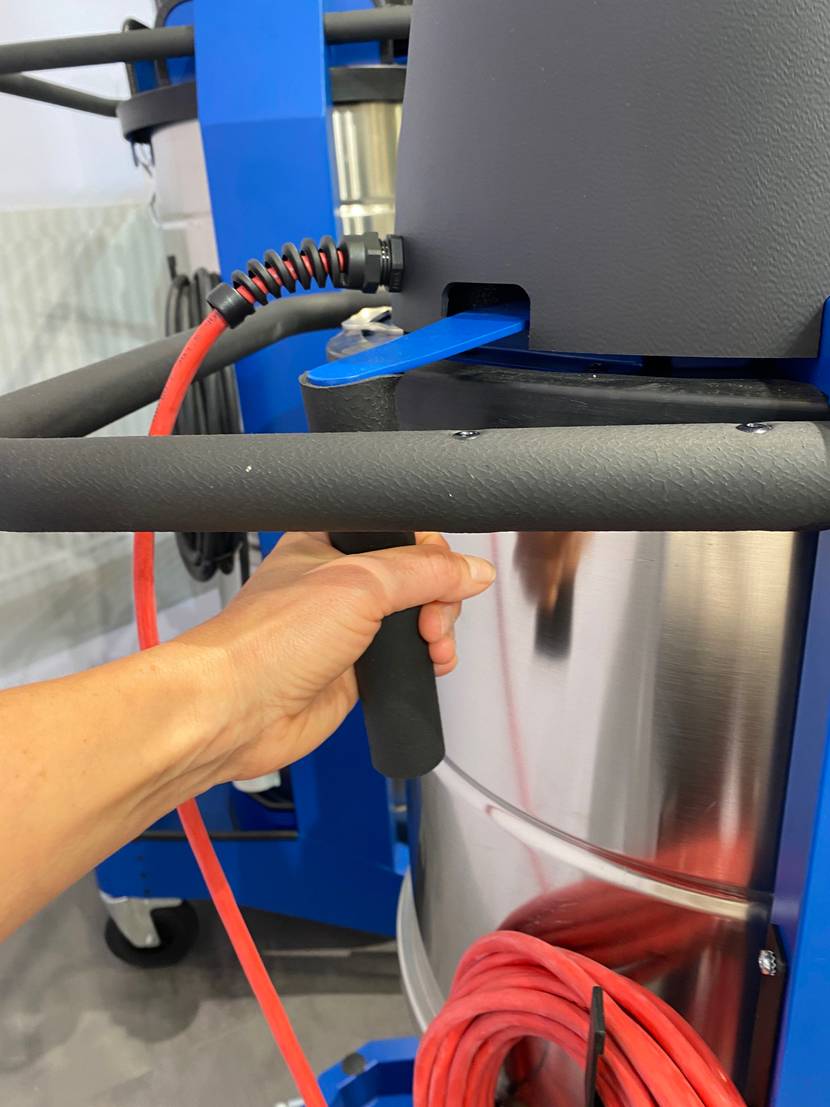 Industriestaubsauger-Test: Detailaufnahme eines Edelstahl-Behälters inklusive gummiertem Griff und orangem Stromkabel.