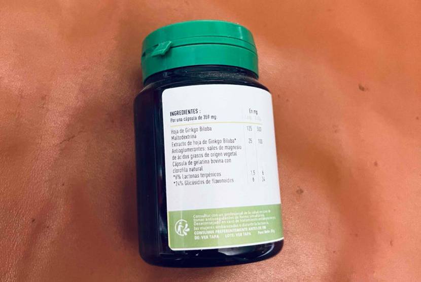 Getestete Ginkgo-Tabletten in einer lichtdichten Kunststoff-Dose inklusive grünem Deckel sowie weißem Aufkleber mit Produktbeschreibung auf kupferfarbigem Hintergrund.