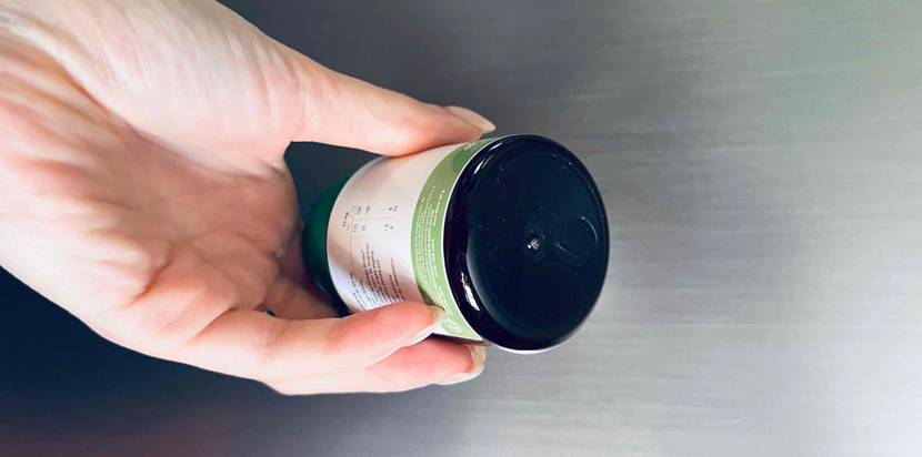 Ginkgo-Tabletten im Test: Hand hält eine lichtdichte Kunststoff-Dose vor hellgrauem Hintergrund.