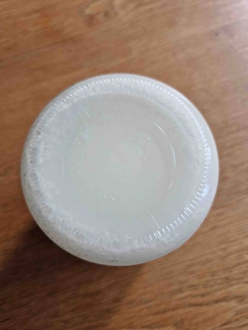 Getestet: Ein Glas Kokosöl steht auf dem Kopf auf einem Holztisch.