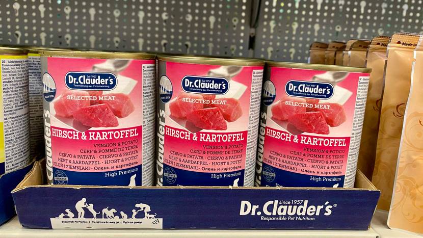 Im Test: Mehrere Dosen des Nassfutters für Hunde in einem Verkaufsregal neben anderen Produkten.