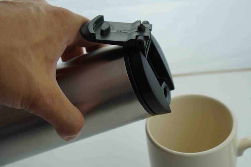 Thermoskanne-Test: Thermoskanne wird zum Ausschenken auf eine Tasse aufgesetzt.