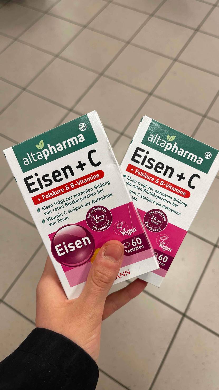 Eisentabletten getestet: Eine Hand hält zwei Packungen wie ein V überkreuzt.