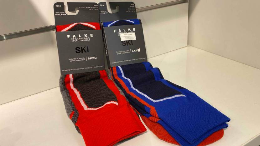 Falke Skisocken im Test: blaue und rote Skisocken für unterschiedliche Wetterbedingungen sind auf einem Verkaufsregal ausgestellt.