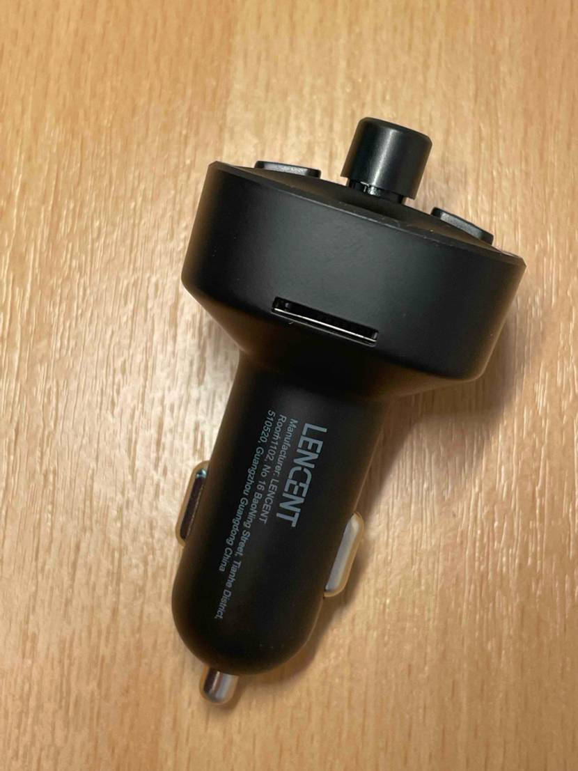 Ansicht von oben auf einen schwarzen FM-Transmitter im Test inklusive Adapter für Zigarettenanzünder-Anschlüsse.