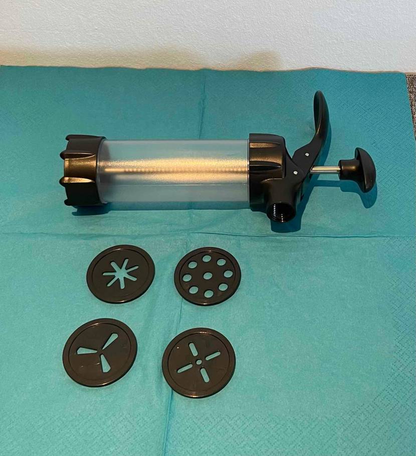 Gebäckpresse im Test liegt quer über vier Formen auf blauer Serviette.