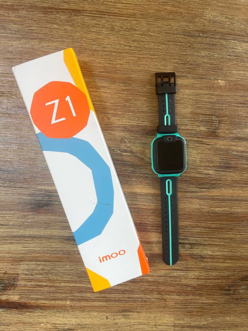 Eine getestete GPS-Uhr neben der Verpackung auf einem Holztisch.