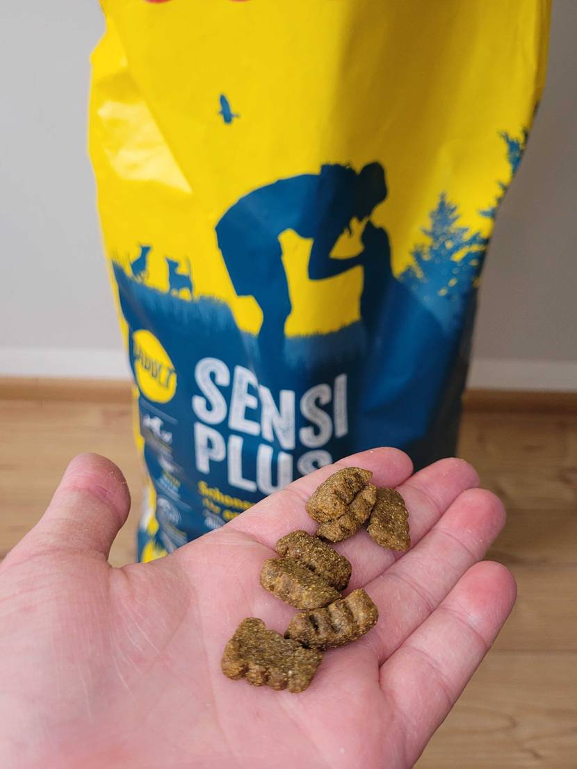 Hand mit Josera Hundefutter vor Beutel.