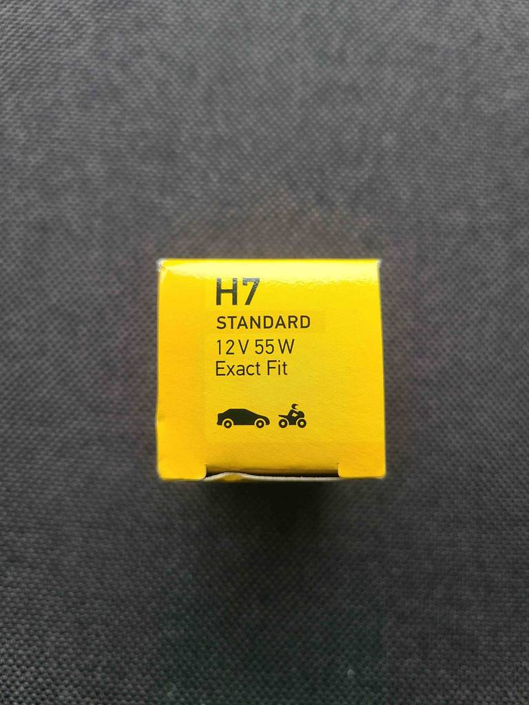 Aufnahme des Deckels einer, auf schwarzem Untergrund stehenden, gelben Schachtel mit der Standard-H7-Birne im Test.