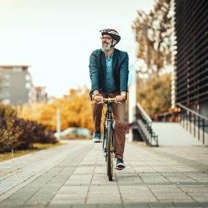 aelterer mann faehrt fahrrad mit fahrradhelm
