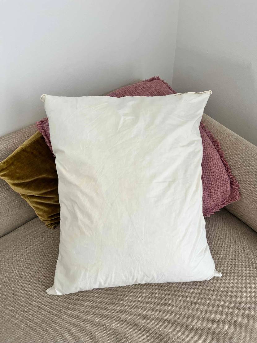 Ikea Kopfkissen getestet: ein weißes Kissen steht vor zwei anderen farbigen Kissen auf einem Sofa.